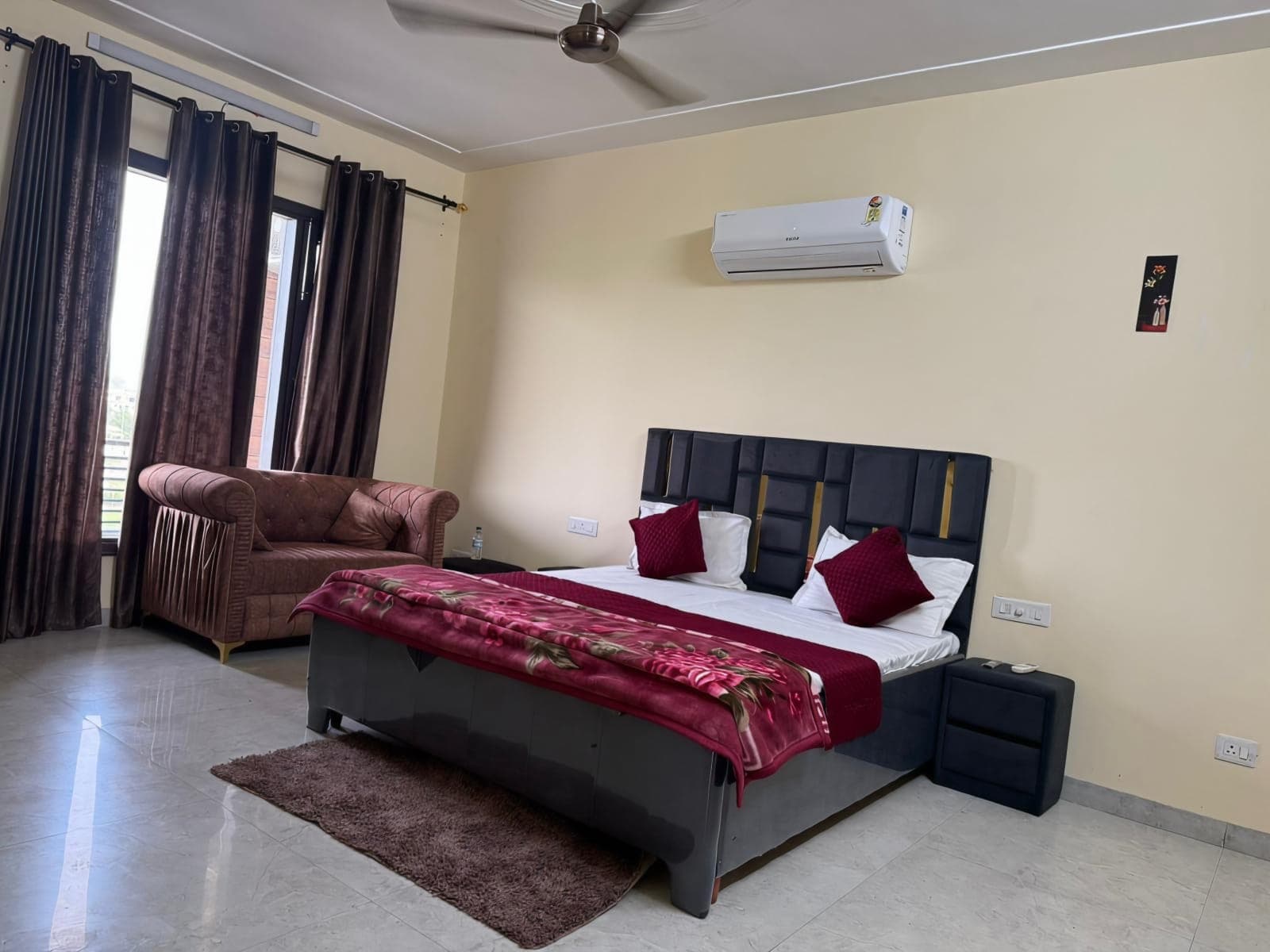 Sunlit air-conditioned bedroom with double bed and sofa at Jastej House
